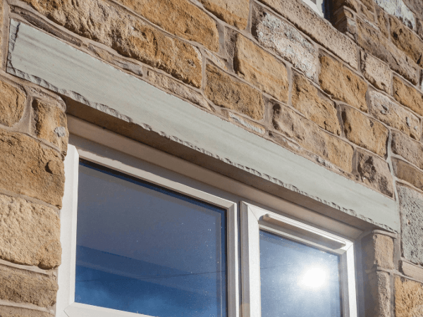 A trickle vent above a window set in a Cotswold stone wall