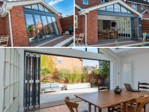 Grey bi folding doors on a brick-built gable extension with grey shaped windows above the bi-folds.